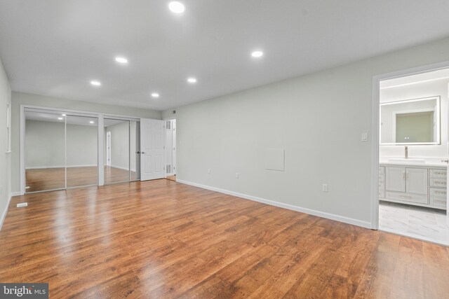 7724 Central Ave, Pasadena, MD 21122 - unfurnished bedroom with multiple closets, wood finished floors, recessed lighting, and connected bathroom
