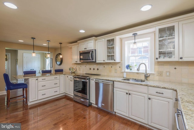620 Laurel Rd, Springfield, PA 19064 - kitchen with stainless steel appliances, a peninsula, a breakfast bar, white cabinetry, and decorative light fixtures