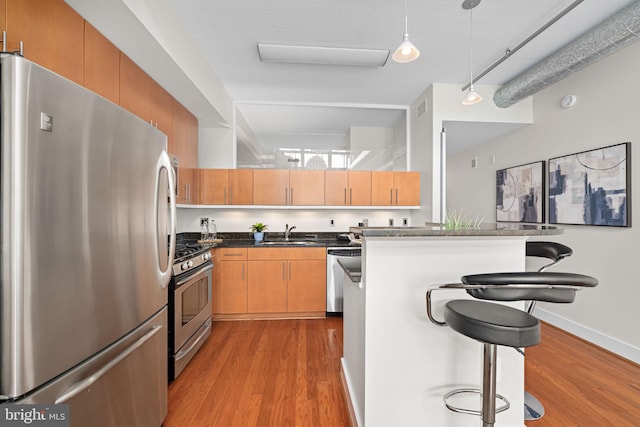 1390 Kenyon St NW Unit 524, Washington, DC 20010 - kitchen featuring appliances with stainless steel finishes, wood finished floors, a breakfast bar area, and dark countertops