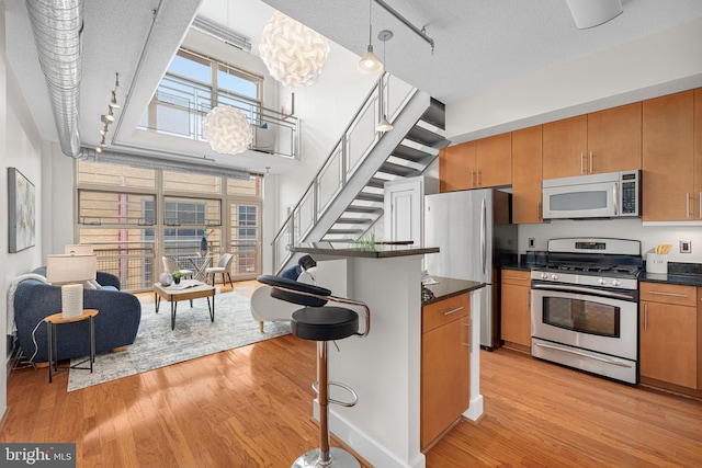 1390 Kenyon St NW Unit 524, Washington, DC 20010 - kitchen featuring appliances with stainless steel finishes, dark countertops, a breakfast bar area, track lighting, and a textured ceiling