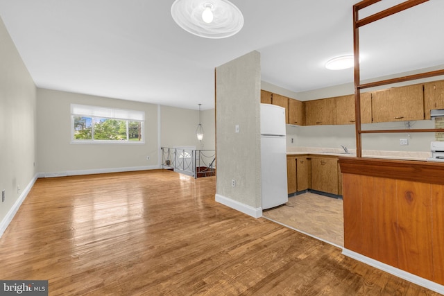 8000 Dellwood Ave, Glenarden, MD 20706 - kitchen featuring freestanding refrigerator, light wood-type flooring, light countertops, brown cabinetry, and open floor plan