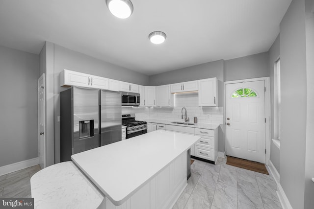 1002 W 9th St, Wilmington, DE 19806 - kitchen featuring appliances with stainless steel finishes, white cabinets, light countertops, a center island, and backsplash