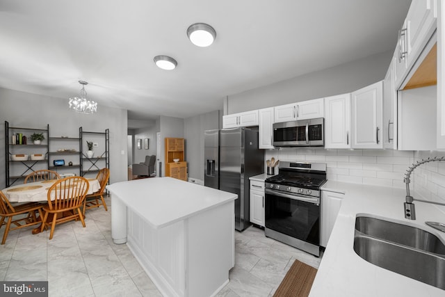 1002 W 9th St, Wilmington, DE 19806 - kitchen featuring stainless steel appliances, light countertops, a kitchen island, white cabinets, and decorative backsplash