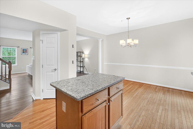 13102 Alpine Dr Unit 2502, Germantown, MD 20874 - kitchen featuring light wood finished floors, a chandelier, a kitchen island, pendant lighting, and light stone countertops