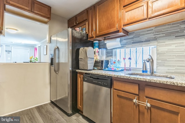 1009 Jansen Ave, Capitol Heights, MD 20743 - kitchen featuring stainless steel appliances, wood finished floors, brown cabinetry, backsplash, and light stone countertops