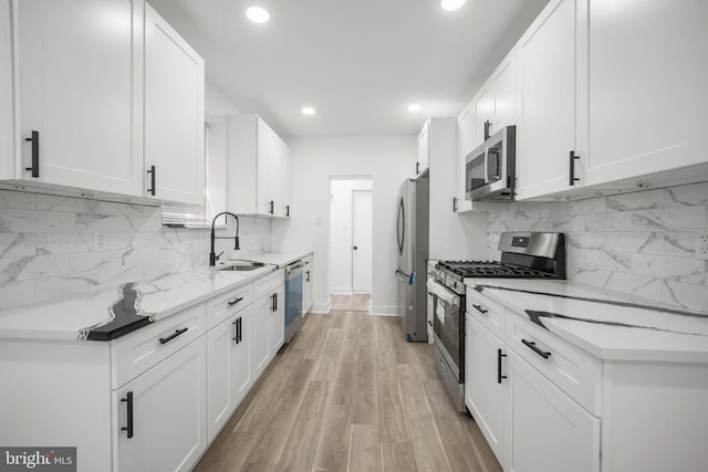 239 Rubicam St, Philadelphia, PA 19120 - kitchen with stainless steel appliances, recessed lighting, backsplash, white cabinets, and light wood-style flooring