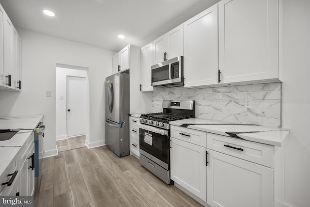 239 Rubicam St, Philadelphia, PA 19120 - kitchen featuring appliances with stainless steel finishes, tasteful backsplash, white cabinetry, light stone countertops, and light wood finished floors