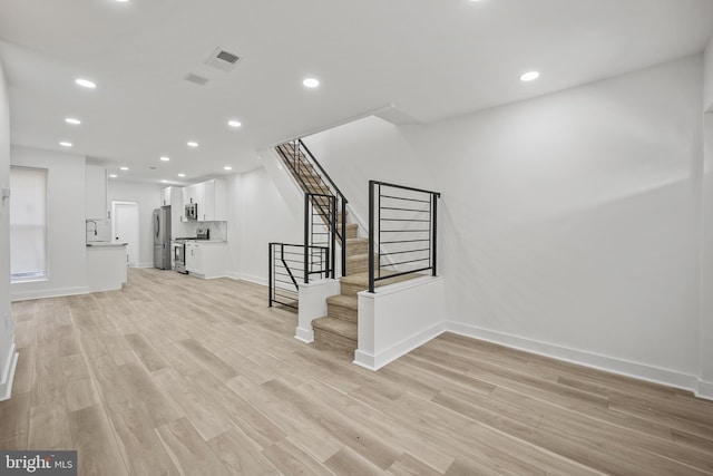 239 Rubicam St, Philadelphia, PA 19120 - unfurnished living room with light wood-style floors, stairway, and recessed lighting