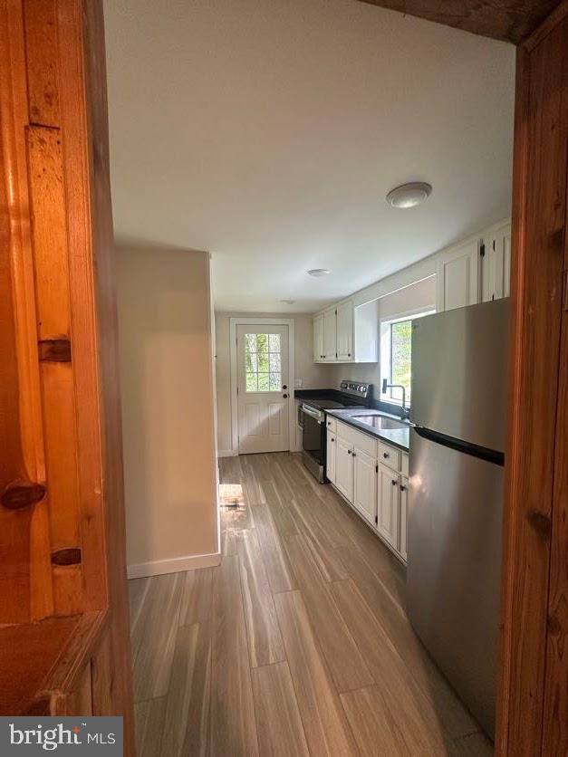 556 Trapper Ridge Ln, Hedgesville, WV 25427 - kitchen with appliances with stainless steel finishes, light wood-style flooring, white cabinets, dark countertops, and plenty of natural light