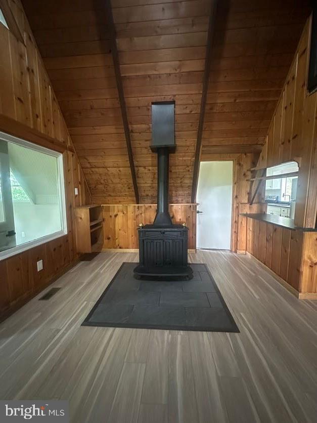 556 Trapper Ridge Ln, Hedgesville, WV 25427 - detailed view of wood finished floors, wood walls, a wood stove, and a wood ceiling with exposed beams