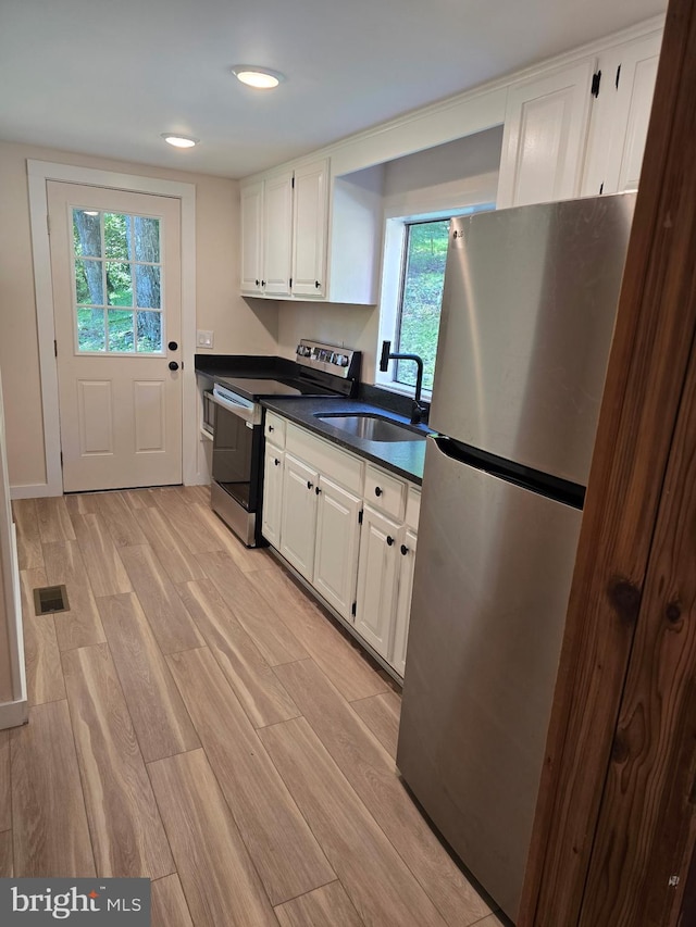 556 Trapper Ridge Ln, Hedgesville, WV 25427 - kitchen with appliances with stainless steel finishes, light wood-style floors, white cabinets, and healthy amount of natural light