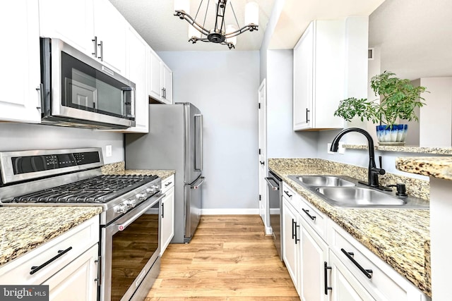 1111 25th St NW Unit 521, Washington, DC 20037 - kitchen featuring appliances with stainless steel finishes, light wood-style flooring, white cabinetry, a chandelier, and light stone counters
