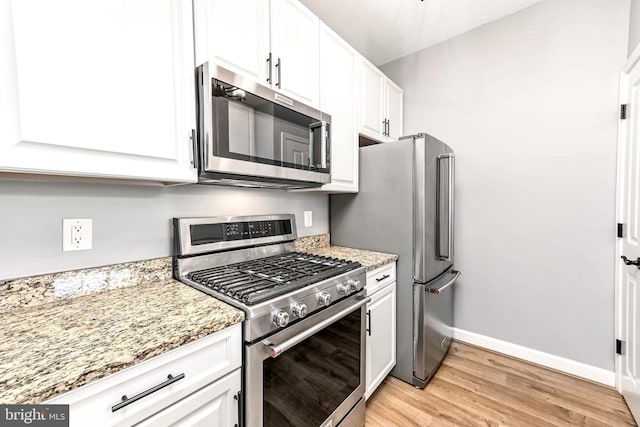 1111 25th St NW Unit 521, Washington, DC 20037 - kitchen with stainless steel appliances, light wood-type flooring, white cabinetry, and light stone counters