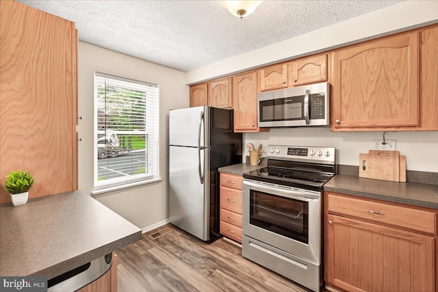 12420 Valleyside Way, Germantown, MD 20874 - kitchen with appliances with stainless steel finishes, dark countertops, wood finished floors, a textured ceiling, and light brown cabinetry