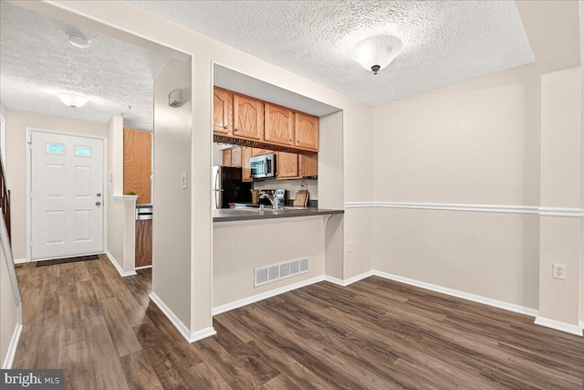 12420 Valleyside Way, Germantown, MD 20874 - kitchen with a textured ceiling, stainless steel microwave, dark wood finished floors, freestanding refrigerator, and dark countertops