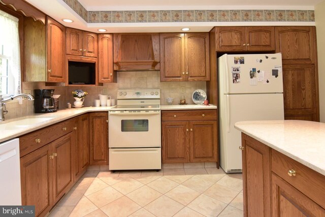 401 Antietam Rd, Reading, PA 19606 - kitchen featuring white appliances, premium range hood, backsplash, brown cabinetry, and recessed lighting