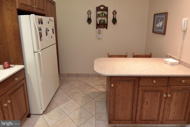 401 Antietam Rd, Reading, PA 19606 - kitchen featuring freestanding refrigerator, light countertops, and brown cabinetry