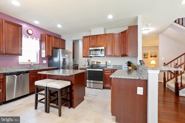 1712 Renaissance Dr, Baltimore, MD 21221 - kitchen with stainless steel appliances, a breakfast bar area, a peninsula, light stone counters, and recessed lighting
