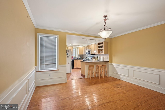 453 Hermitage St, Philadelphia, PA 19128 - kitchen with stainless steel microwave, a breakfast bar area, light wood-type flooring, a peninsula, and ornamental molding