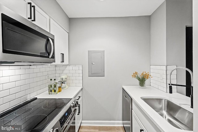 1801 Calvert St NW Unit 204, Washington, DC 20009 - kitchen with stainless steel appliances, electric panel, white cabinetry, decorative backsplash, and light countertops