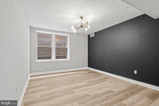 1801 Calvert St NW Unit 204, Washington, DC 20009 - empty room with a chandelier, light wood-style floors, an accent wall, and brick wall