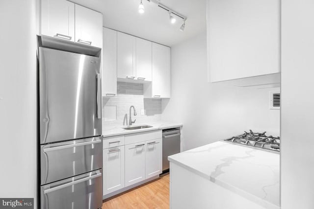 3601 5th St S Unit 408, Arlington, VA 22204 - kitchen with appliances with stainless steel finishes, white cabinets, tasteful backsplash, light stone countertops, and light wood-style flooring