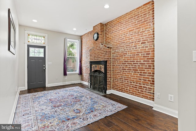3016 Dillon St, Baltimore, MD 21224 - entryway featuring brick wall, wood-type flooring, a brick fireplace, and recessed lighting