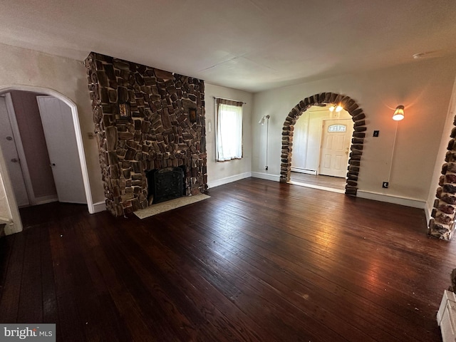 2326 Franklin Ave, Morton, PA 19070 - unfurnished living room featuring arched walkways, hardwood / wood-style floors, and a stone fireplace