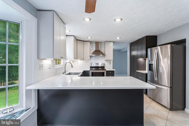 1240 Windmill Ln, Silver Spring, MD 20905 - kitchen featuring appliances with stainless steel finishes, wall chimney range hood, a peninsula, backsplash, and light tile patterned floors