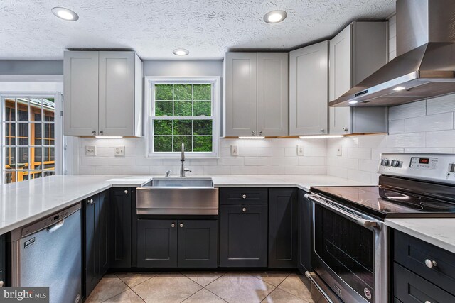 1240 Windmill Ln, Silver Spring, MD 20905 - kitchen featuring wall chimney range hood, stainless steel appliances, tasteful backsplash, light tile patterned floors, and light stone counters