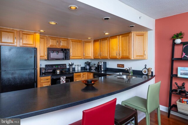 2001 Hamilton St Unit 925, Philadelphia, PA 19130 - kitchen featuring black appliances, recessed lighting, a kitchen breakfast bar, a peninsula, and wood finished floors