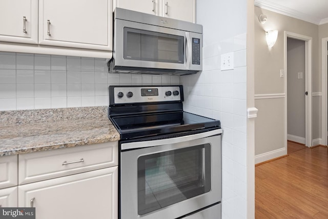 1901 John F Kennedy Blvd Unit 1414, Philadelphia, PA 19103 - kitchen with appliances with stainless steel finishes, ornamental molding, white cabinets, light wood-type flooring, and tasteful backsplash