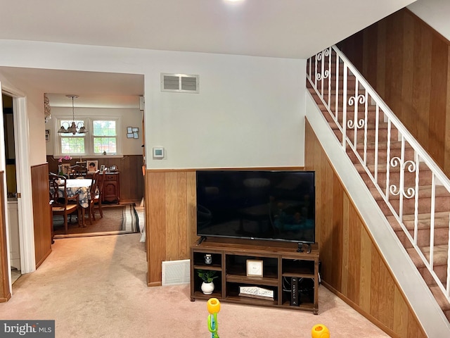 9013 Ashton Rd, Philadelphia, PA 19136 - living area featuring wooden walls, carpet, a wainscoted wall, stairs, and a chandelier