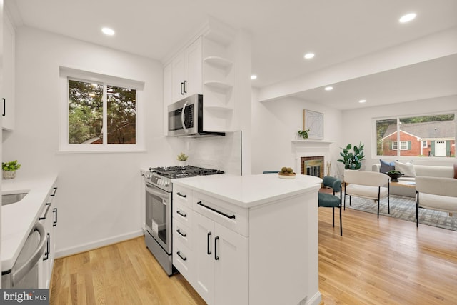 6232 18th Rd N, Arlington, VA 22205 - kitchen featuring stainless steel appliances, light wood-type flooring, a brick fireplace, open shelves, and white cabinets