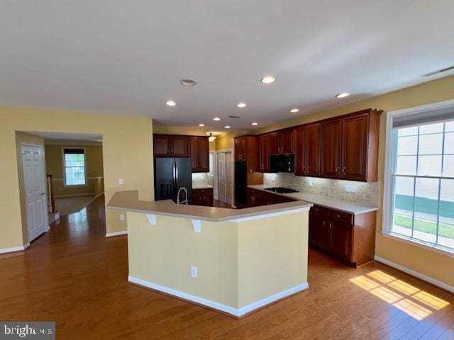 12410 Coastal Marsh Dr, Berlin, MD 21811 - kitchen with black appliances, wood finished floors, a large island, backsplash, and light countertops