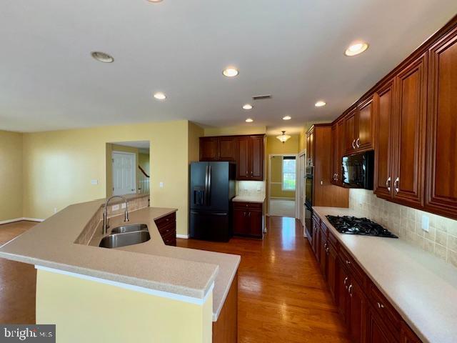 12410 Coastal Marsh Dr, Berlin, MD 21811 - kitchen with black appliances, an island with sink, decorative backsplash, recessed lighting, and light countertops