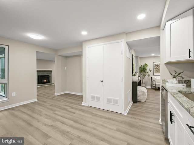 9124 Goldamber Garth, Columbia, MD 21045 - kitchen with light wood-style floors, white cabinets, light stone countertops, a brick fireplace, and dishwasher