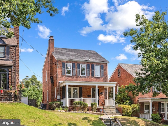 1928 Shepherd St NE, Washington, DC 20018 - view of front facade featuring a porch, brick siding, a front lawn, and a chimney