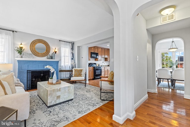1928 Shepherd St NE, Washington, DC 20018 - living room with arched walkways, light wood-style flooring, and a brick fireplace