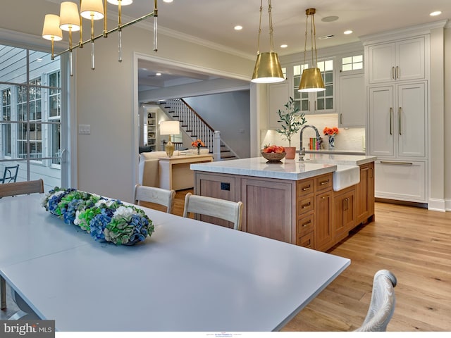 204 Walnut Tree Ln, Malvern, PA 19355 - kitchen featuring a center island with sink, crown molding, light wood-style flooring, glass insert cabinets, and decorative backsplash