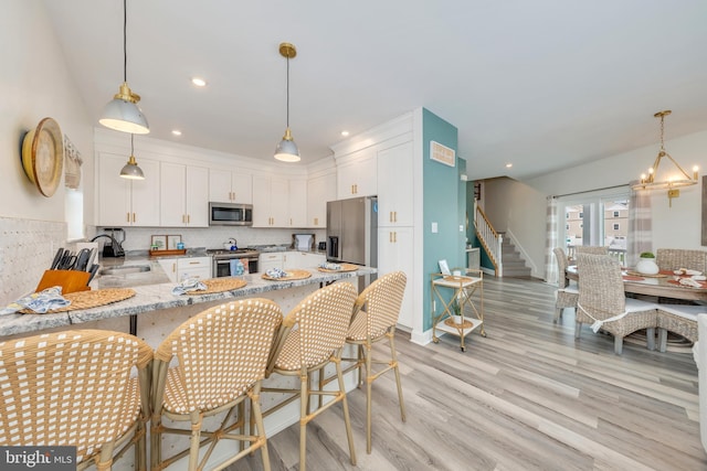 209 N New York Ave Unit 2, North Wildwood, NJ 08260 - kitchen featuring appliances with stainless steel finishes, white cabinets, light wood-style floors, a peninsula, and decorative backsplash