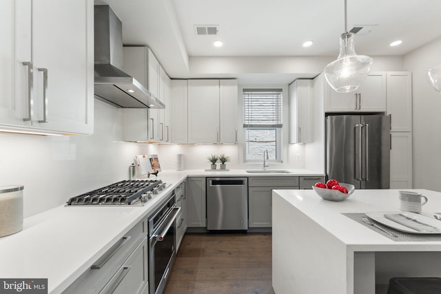 417 4th St SE Unit 2, Washington, DC 20003 - kitchen featuring stainless steel appliances, wall chimney range hood, light countertops, dark wood finished floors, and hanging light fixtures