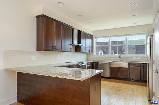 407 Fennel Rd, Crozet, VA 22932 - kitchen with appliances with stainless steel finishes, a peninsula, light stone counters, light wood-style flooring, and backsplash