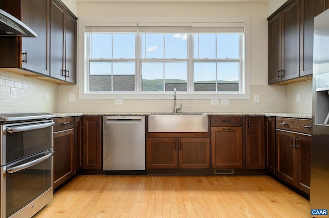407 Fennel Rd, Crozet, VA 22932 - kitchen with appliances with stainless steel finishes, ventilation hood, light wood-style flooring, and tasteful backsplash