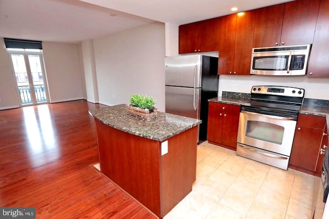 155 Potomac Psge Unit 527, Oxon Hill, MD 20745 - kitchen featuring appliances with stainless steel finishes, a kitchen island, dark stone countertops, light wood-style floors, and open floor plan