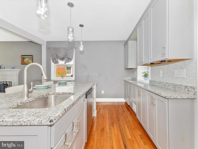 507 Kerwin Ct, Silver Spring, MD 20901 - kitchen with decorative backsplash, light wood-style floors, pendant lighting, stainless steel dishwasher, and light stone countertops