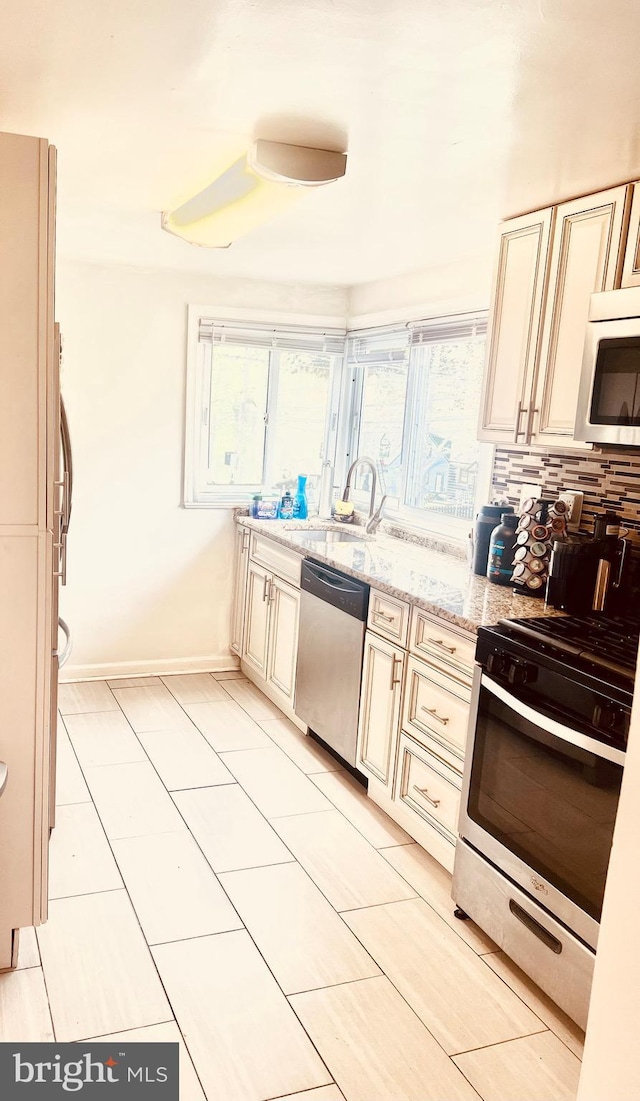 6011 State St, Cheverly, MD 20785 - kitchen with stainless steel appliances, cream cabinetry, light stone counters, and decorative backsplash