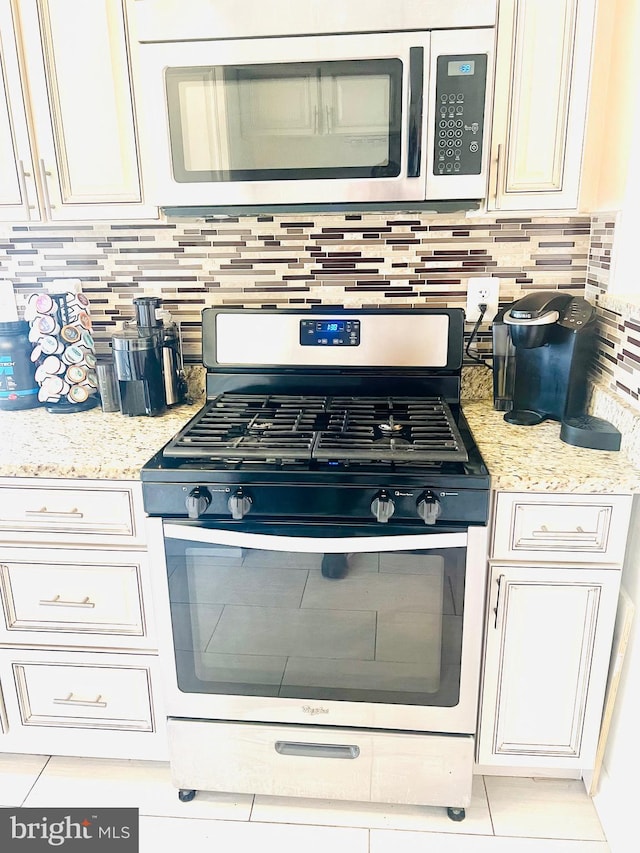 6011 State St, Cheverly, MD 20785 - kitchen featuring appliances with stainless steel finishes, white cabinets, backsplash, and light stone counters