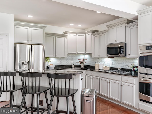 15164 Santander Dr, Gainesville, VA 20155 - kitchen with stainless steel appliances, a kitchen bar, decorative backsplash, a center island, and recessed lighting