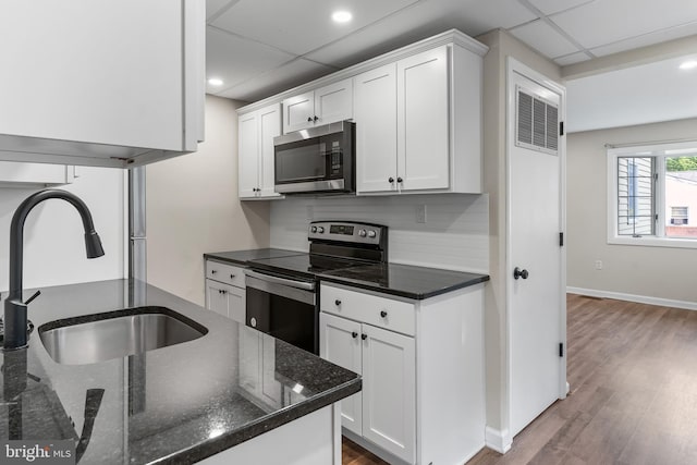 1557 Fairview Ave, Langhorne, PA 19047 - kitchen featuring appliances with stainless steel finishes, white cabinets, wood finished floors, dark stone counters, and recessed lighting